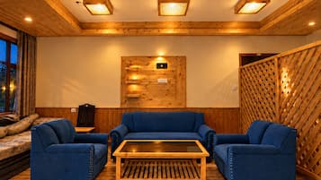 Una stanza con travi in legno al soffitto, un pannello di legno a parete con una radio montata e un divano blu.