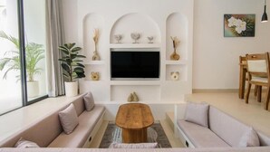 En moderne stue med fjernsyn, sofa, sofabord og pyngeting.