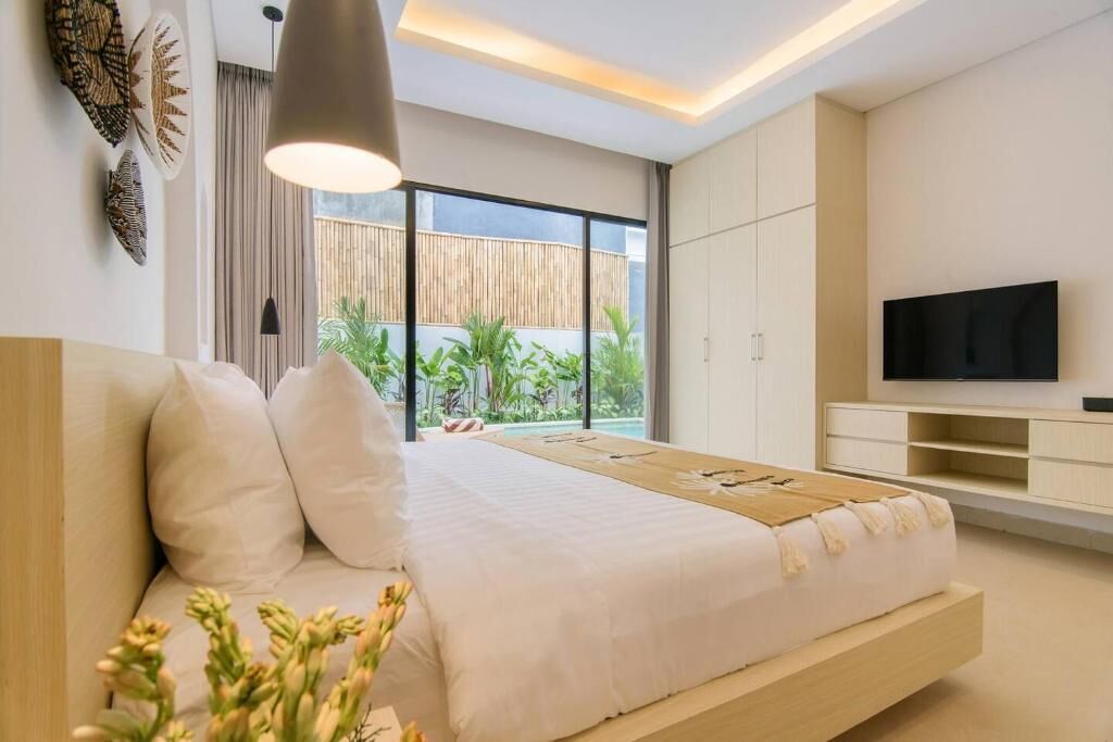Un dormitorio moderno con cama, mesitas de noche, televisión y vistas al exterior.