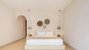 Un dormitorio minimalista con una cama centrada, flanqueada por mesitas de noche con lámparas.