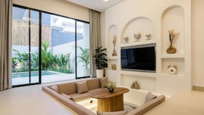 Una sala de estar moderna con un sofá grande, una mesa de centro y un televisor montado en la pared.