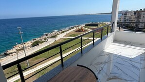 Un balcó amb vista al mar, una taula de fusta i un paviment de rajoles.