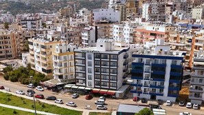 A coastal urban area with a prominent building labeled 'KORASION' and a rocky shoreline with clear water. - Korasion Otel (Silifke)