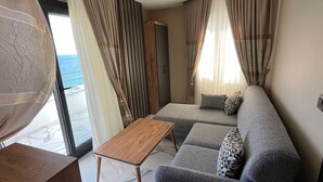 Un saló modern amb un sofà, una taula de centre de fusta i vista al mar.