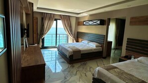 Habitació d'hotel amb un llit gran, un escriptori i vistes al mar.