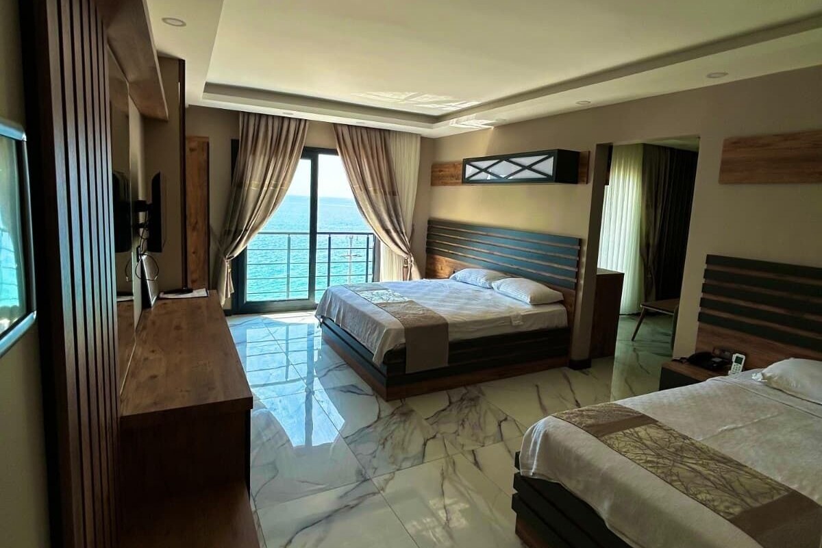 A hotel room with a large bed, a desk, and a view of the sea.