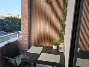 Un balcon avec une table et des chaises en bois, une plante en pot et une lanterne.