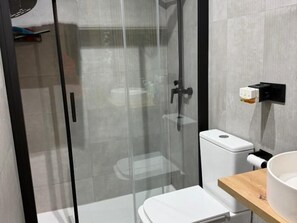Une salle de bain moderne avec une douche à parois de verre, des toilettes et un lavabo avec un receveur.