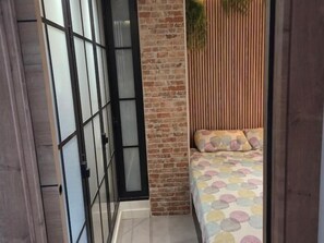 Une pièce avec un lit, un mur en briques et une porte coulissante.