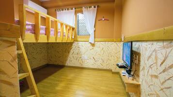 A room with a bunk bed, a window with curtains, a television, and a wooden floor.