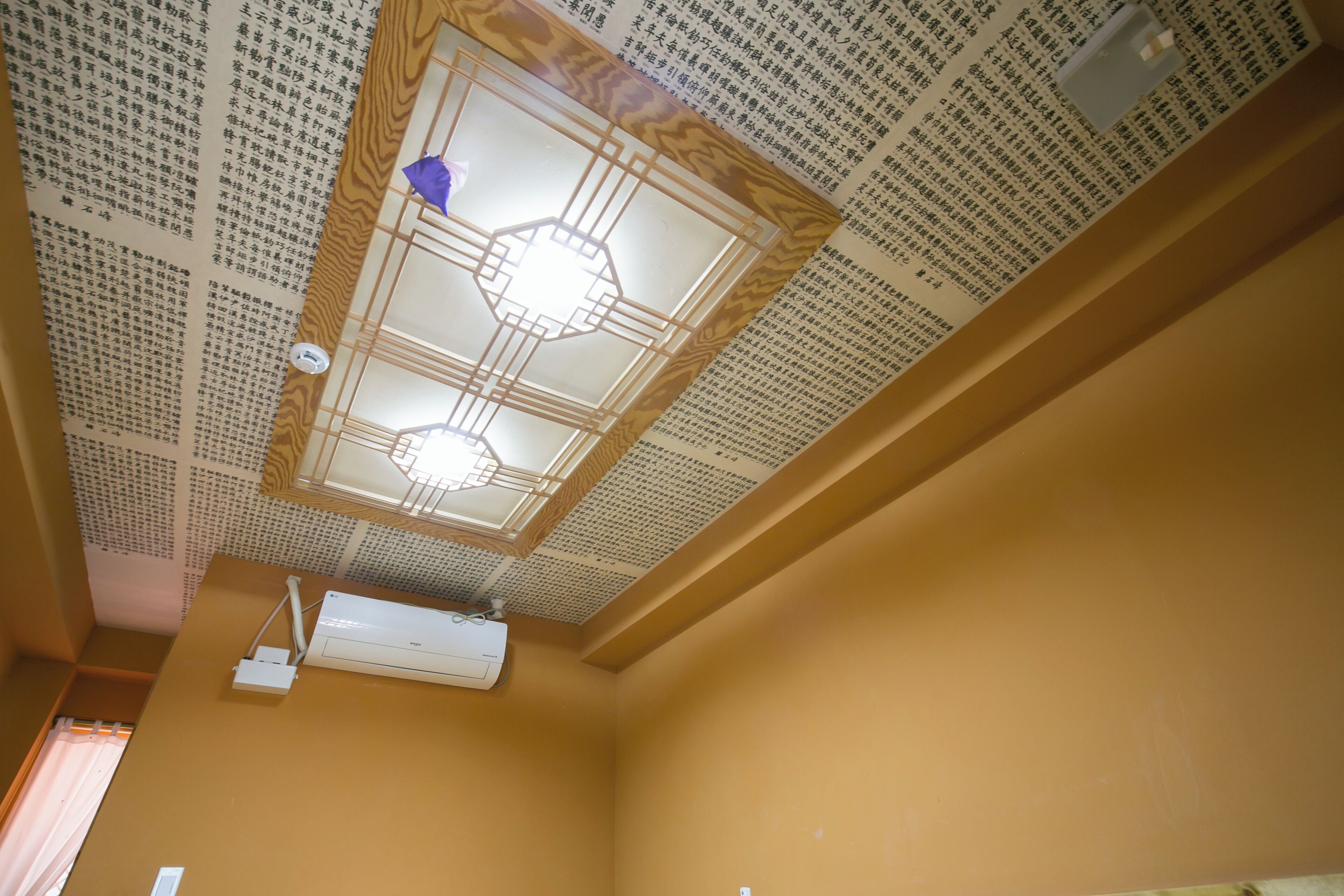 A room with a ceiling fan, an air conditioning unit, and a wooden ceiling design.