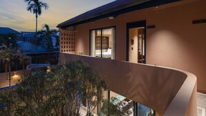 A modern building with a balcony overlooking a garden.