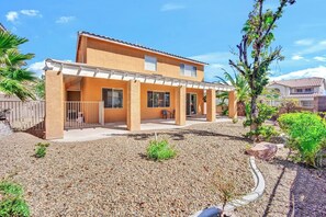 Una casa de dos pisos con un porche cubierto, un camino de entrada de grava y un pequeño jardín con diversas plantas.