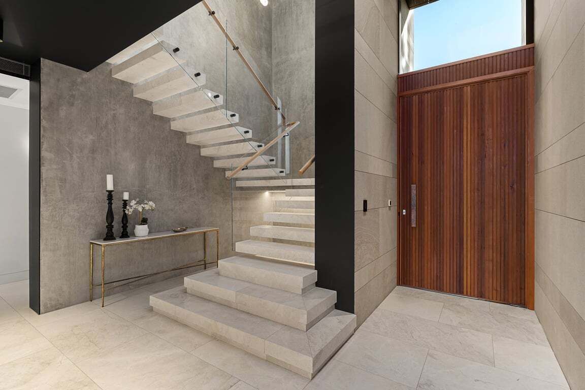 Un intérieur moderne avec un escalier, une console et une porte en bois.