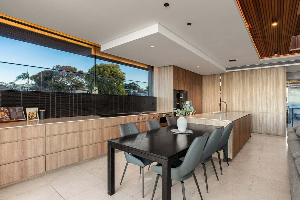 A modern kitchen with a dining area, large windows, and a view of the city.