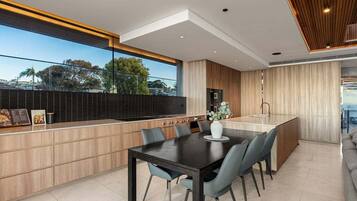 A modern kitchen with a dining area, large windows, and a view of the city.