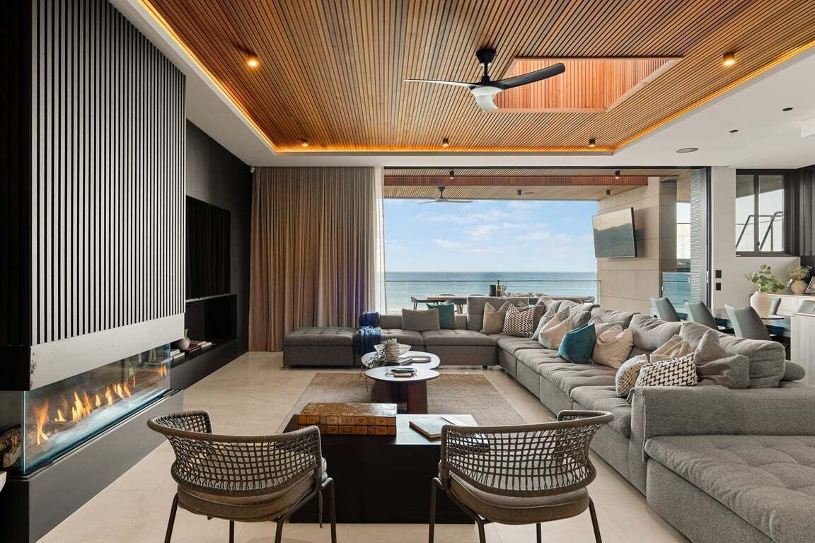 Un salon moderne avec un grand canapé, une cheminée et une vue sur la mer.