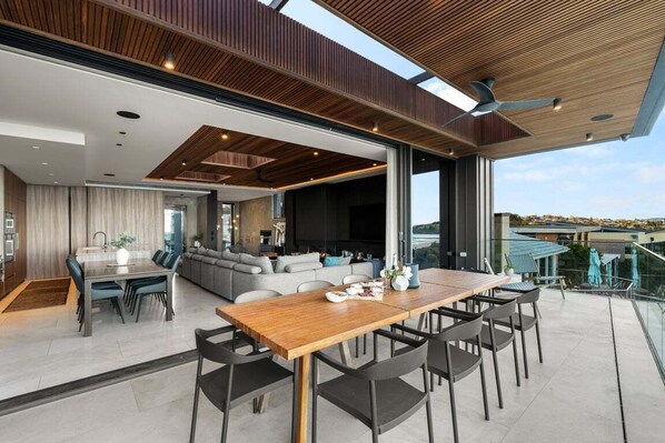 A spacious living area with a wooden dining table, comfortable seating, and a large window offering a view of the cityscape.