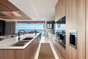 Una cocina moderna con una isla grande, electrodomésticos integrados y vistas al océano.