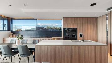 A modern kitchen with a central island, wooden cabinetry, and a large window overlooking a cityscape.
