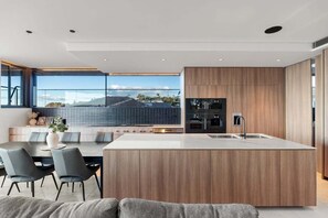 Una cocina moderna con una isla central, armarios de madera y un amplio ventanal con vistas a la ciudad.