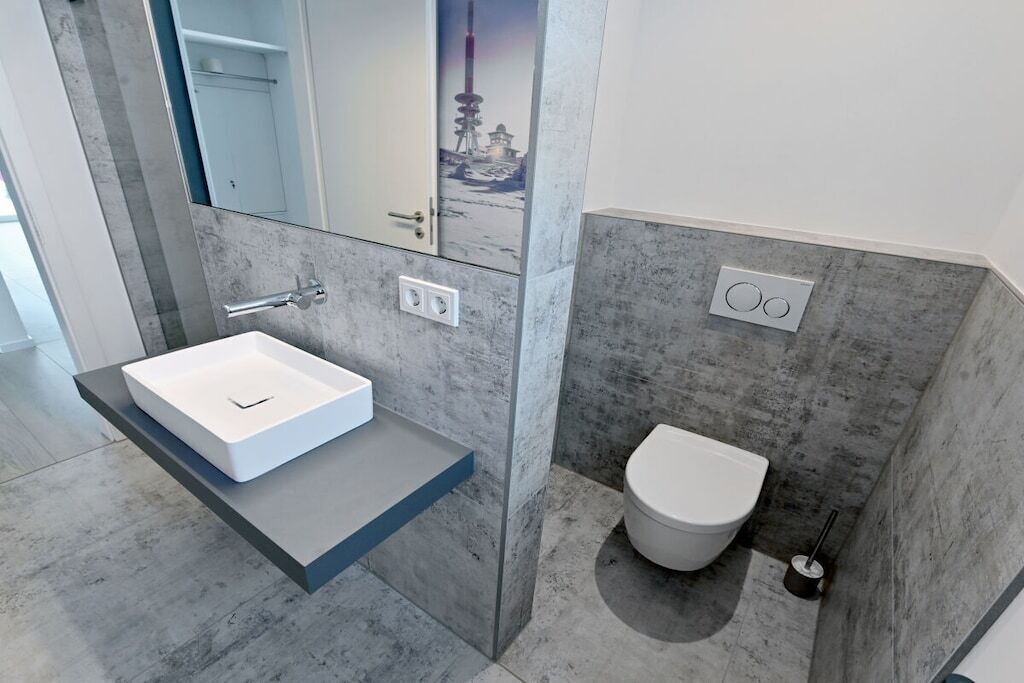 Une salle de bain moderne avec un lavabo blanc, des toilettes et un miroir.