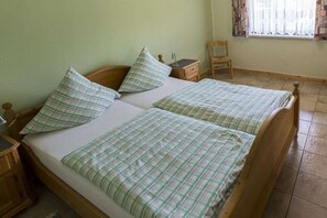 Ein Zimmer mit zwei hölzernen Betten, jeweils ausgestattet mit einem passenden Kopfkissen und einem Nachttisch.