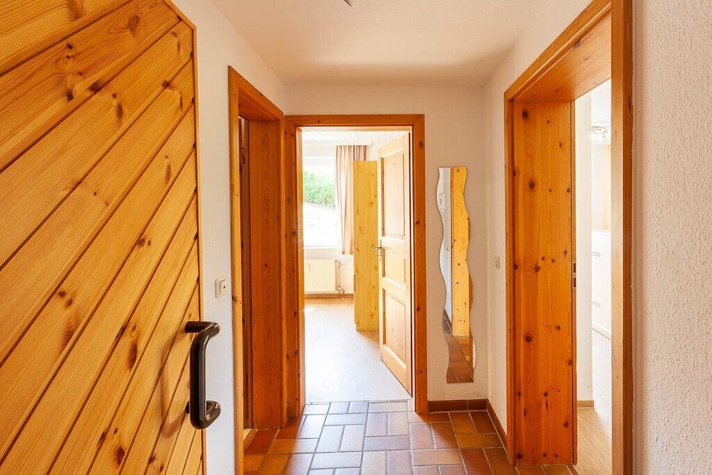 Un couloir avec des portes en bois et un sol carrelé.