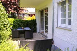 A patio with a table and chairs, a white exterior wall, and a hedge. - Holiday apartment with 2 bedrooms (Braunlage)