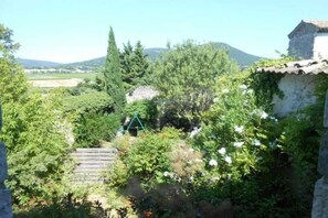 A rustic stone building with a traditional tiled roof, surrounded by lush greenery and a clear sky. - Maffone la laupie gîte COCO (La Laupie)