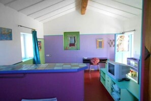 A room with a purple wall, a small window, a television, and a chair. - Maffone la laupie gîte COCO (La Laupie)