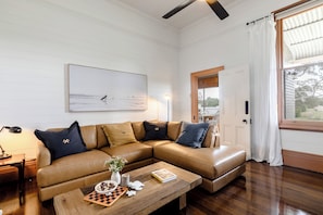 A living room with a brown leather sofa, a wooden coffee table with a chessboard, a vase with flowers, and a framed picture on the wall. - Mid North Coast Accomodation and Horsestay (Rawdon Island)