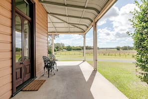 A covered porch with a view of a grassy field and trees. - Mid North Coast Accomodation and Horsestay (Rawdon Island)
