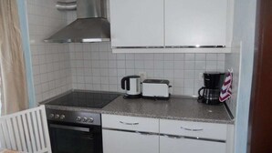 Cozinha compacta com fogão, torradeira e máquina de café.
