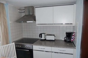 Ett kompakt kök med en spis, brödrost och kaffebryggare.
