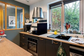 Eine moderne Küche mit Einbauofen, Kaffeemaschine und einem Fenster mit Blick auf Grünflächen.