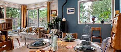Una habitación luminosa con una mesa de comedor preparada para cuatro personas, rodeada de asientos cómodos.