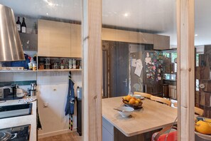 Eine moderne Küche mit Holzausbau, einer Edelstahl-Dunstabzugshaube und einem Essbereich mit einem Holztisch und Stühlen.