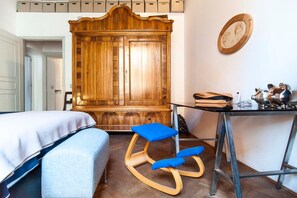 Un dormitorio con un armario de madera, una cama, un escritorio con una silla y una mesita con figuritas de cerdos.