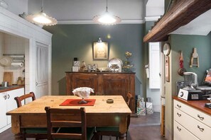 Un comedor con mesa y sillas de madera, un armario con utensilios de cocina y un reloj en la pared.