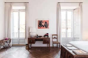 Habitación de hotel con un escritorio de madera, una silla, una cama y una ventana con cortinas.
