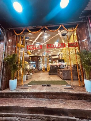 En hotelindgang med receptionsdisk, trappe op til lobbyen og et skilt med teksten 'Natraj Inn'.