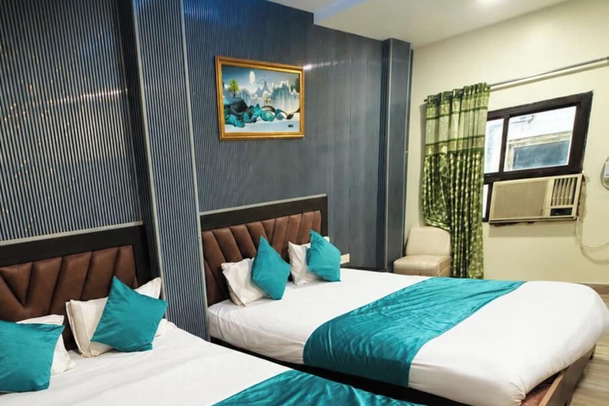 Habitación de hotel con dos camas, un cuadro en la pared y una ventana con cortinas.
