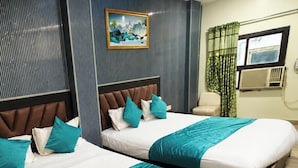 Two beds with headboards, a painting on the wall, and a window with curtains. - HOTE NATRAJ INN  (Varanasi)