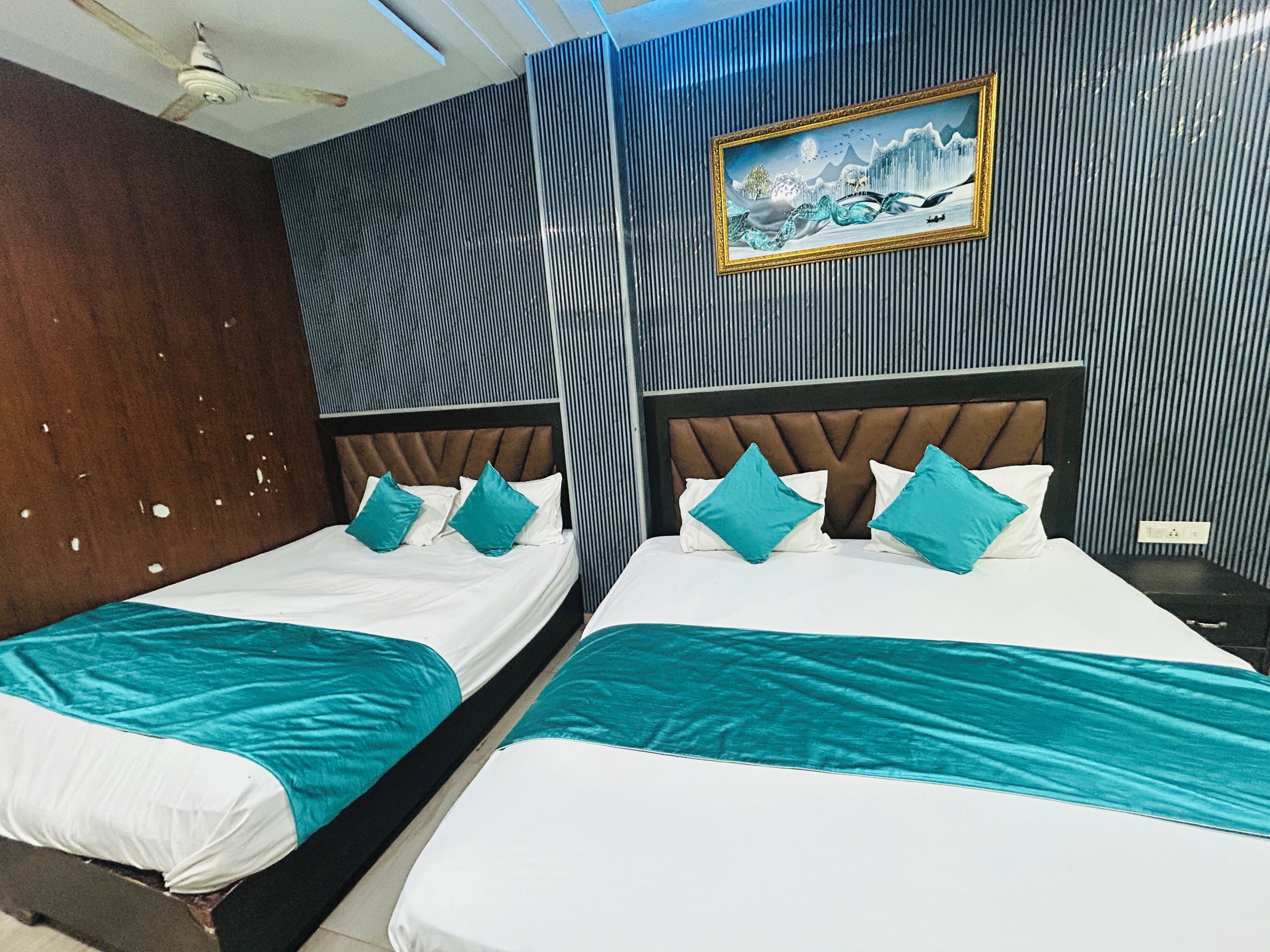 A hotel room with two beds, a ceiling fan, a painting on the wall, and a striped wallpaper design.