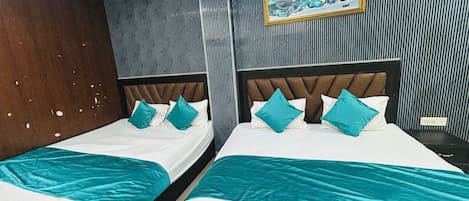 A hotel room with two beds, a ceiling fan, a painting on the wall, and a striped wallpaper design.