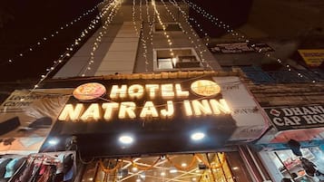 L’extérieur de l’hôtel Natraj Inn se distingue par une enseigne bien visible, une entrée facilement identifiable et des guirlandes lumineuses.