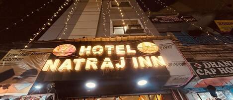Esterno dell'Hotel Natraj Inn con un cartello ben visibile, un ingresso evidente e luci decorative.