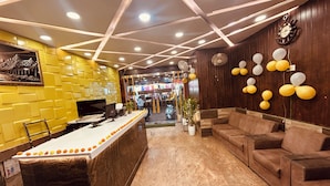 A reception area with a counter, seating, and a wall with a clock. - HOTE NATRAJ INN  (Varanasi)