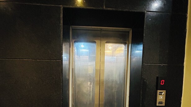 Un ascensor con pantalla digital y puerta de cristal.